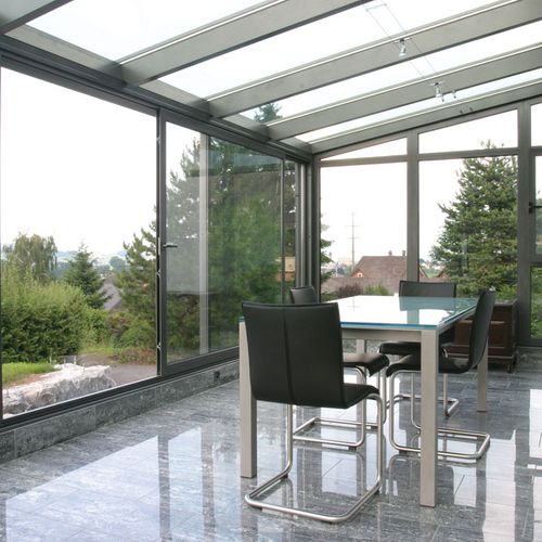 Inneres von Wintergarten aus Glas mit Tisch und Stühlen in Vorarlberg